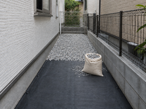 建物と隣家の間に施工した防草シートと砂利